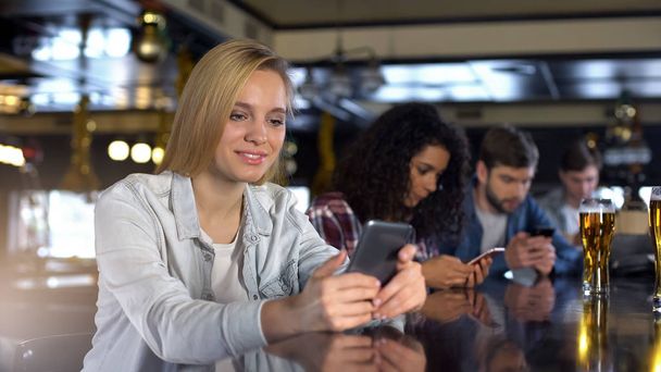 Gruppe von Menschen, die Telefone in Bar benutzen, süchtig nach sozialen Netzwerken Millennials - Foto, Bild
