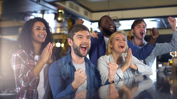 Group of sport fans watching game in bar, rejoicing victory of favorite team - Foto, Bild