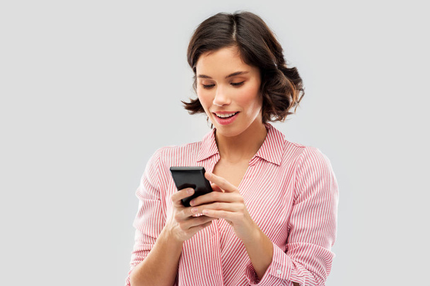 young woman in striped shirt using smartphone - Zdjęcie, obraz