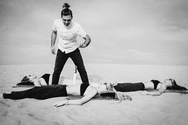 Екстремальні тренування - людина (гуру, майстер) тримає ніж на животі жінки у пустелі. Екстремальне хобі, сила волі, тренування, концепція йоги
 - Фото, зображення