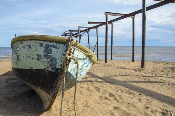 old big fishing boat on the background of the sea, sand and broken Telfer overpass for launching boats in the old fishing village. - Foto, afbeelding