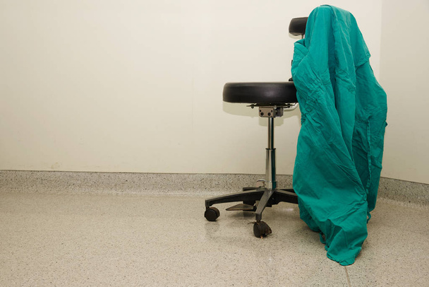 Uniforme quirúrgico colgado en la silla
 - Foto, Imagen