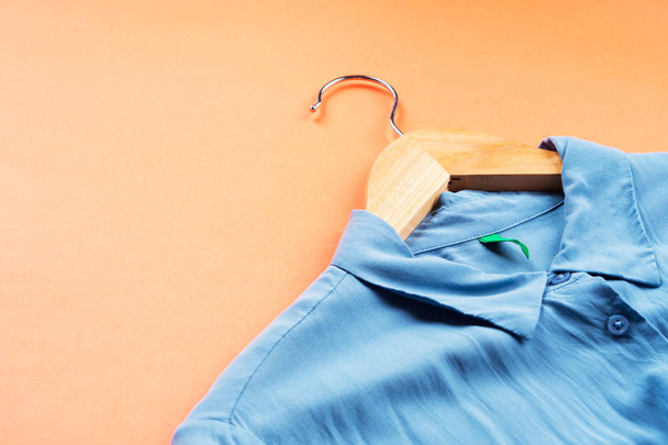 Blue womans shirt on hanger on orange - Zdjęcie, obraz