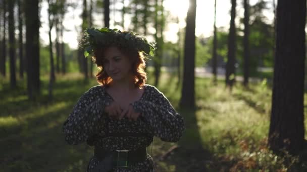 Ayakta: Geleneksel Letonya Ligo yaz ortasında bir Çelenk redhead genç kadın - Beyaz beyaz kız güneşli gün batımında bir kemer ile noktalı bir yaz elbise giyiyor - Video, Çekim
