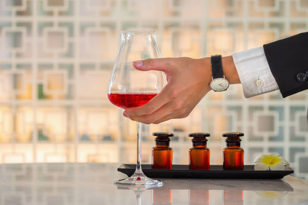 Businessman hand holding a red wine glass on table  inside bar & - Fotografie, Obrázek