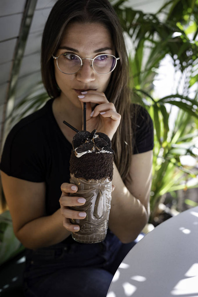 Beautiful women blurred drinking a chocolate shake and cookies on a transparent glass with aboriginal design - Фото, изображение