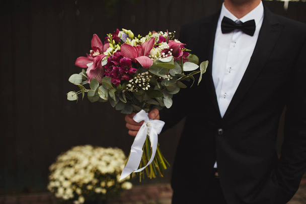 Stylish groom are holding bridal bouquet. Wedding bouquet in man hands - Valokuva, kuva