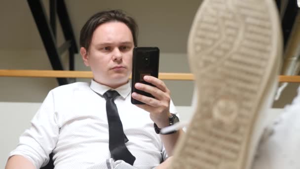 Mladý muž používání telefonu Smartphone na pracovišti - Záběry, video