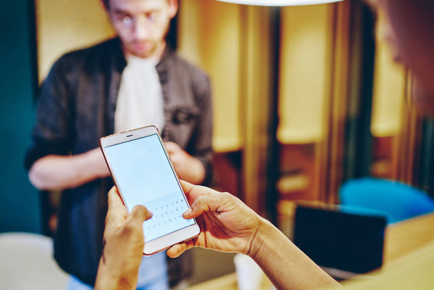 Καλλιεργημένη εικόνα του smartphone στο χέρι της ανδρικής αποστολής μηνυμάτων κειμένου μέσω της εφαρμογής και 4G internet, επιλεκτική εστίαση στο κινητό τηλέφωνο με mock up οθόνη σε θολή φόντο και τύπος silhouett - Φωτογραφία, εικόνα