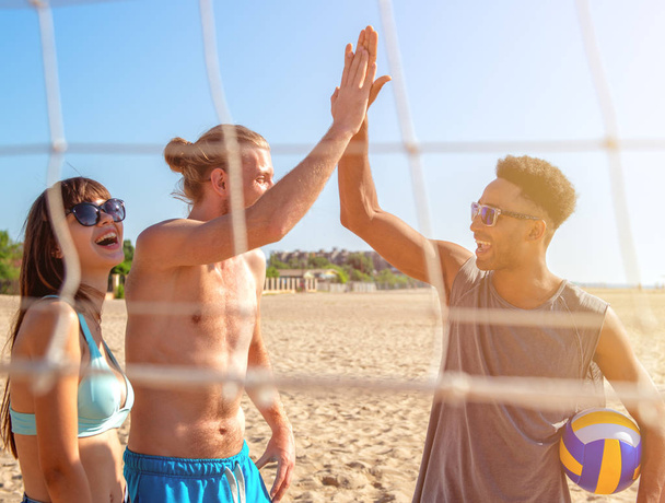 Grupo de amigos brincando na vôlei de praia na praia
 - Foto, Imagem