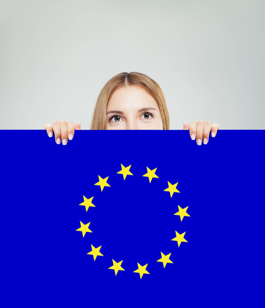 Έννοια της Ευρωπαϊκής Ένωσης με χαρούμενη γυναίκα που δείχνει το υπόβαθρο της σημαίας της ΕΕ - Φωτογραφία, εικόνα