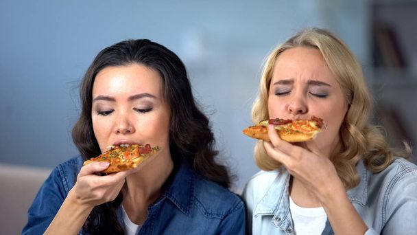 Hungry female friends enjoying delicious pizza, Italian cuisine, food delivery - Photo, Image