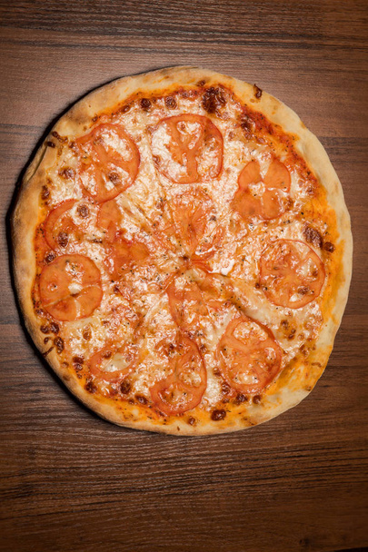 вертикальний вид зверху цілої піци з помідорами і сиром
 - Фото, зображення