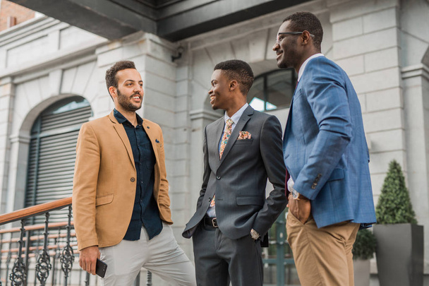 three young friendly men in suits are talking - Φωτογραφία, εικόνα