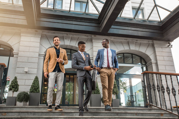 three young friendly men in suits near the building - Photo, Image