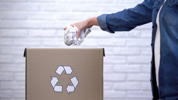 Person throwing paper into trash bin, waste sorting concept, recycling system - Photo, image