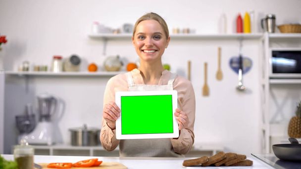 Cheerful woman holding tablet with green screen, cooking blogs and apps template - Foto, afbeelding