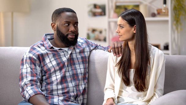 Afro-american boyfriend suspiciously looking at girlfriend, surprise for beloved - Valokuva, kuva