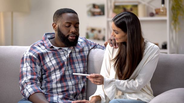Happy lady showing pregnancy test to Afro-American boyfriend, positive result - Zdjęcie, obraz