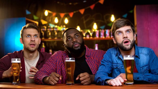 Excited multiracial friends watching sport channel sitting in beer pub, leisure - Φωτογραφία, εικόνα