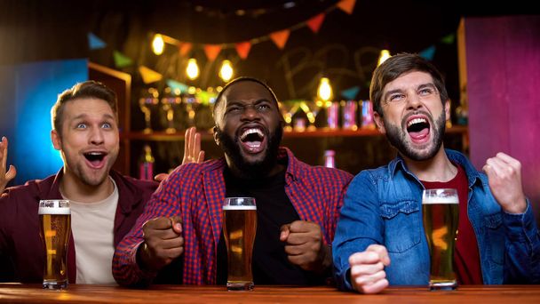 Multiracial male friends supporting favorite football team in bar, results time - Foto, Imagem
