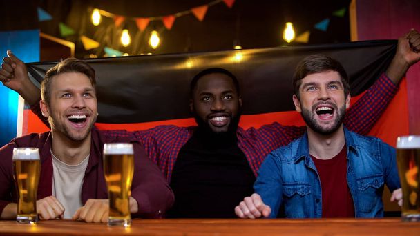 Emotional german football fans celebrating national team winning match in pub - Fotó, kép