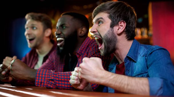 Extremely happy multiracial friends celebrating victory of national boxer in bar - Photo, image