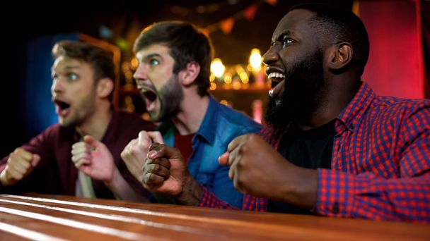 Happy friends celebrating soccer team scoring goal, shouting and gesticulating - 写真・画像