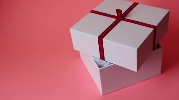 κουτί δώρου με τριαντάφυλλα. Λευκό κουτί δώρου σε ροζ φόντο - Πλάνα, βίντεο