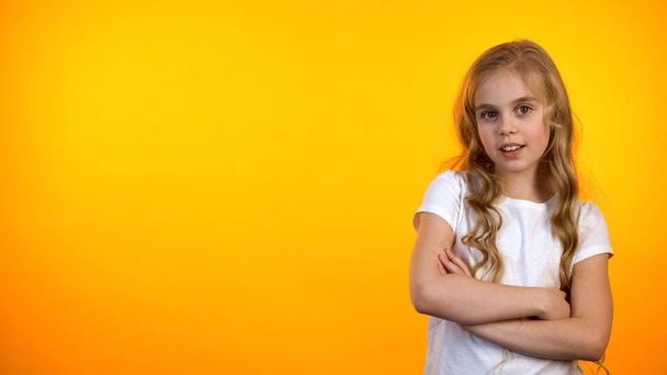 Beautiful girl with hands crossed on chest looking to cam on orange background - Фото, зображення