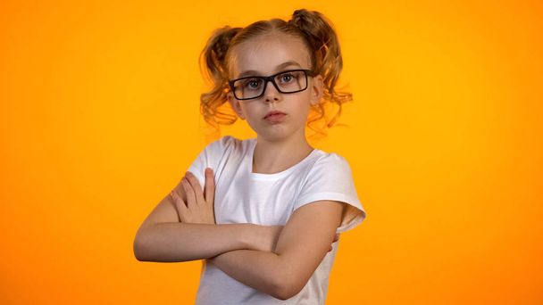 Adorable girl in eyeglasses looking to camera with hands crossed on chest, nerd - Fotografie, Obrázek