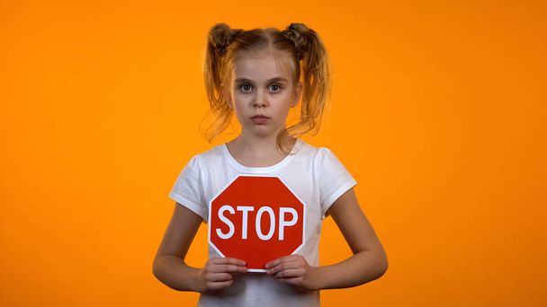 Beautiful girl holding stop sign, family misbehavior, children rights protection - Foto, imagen