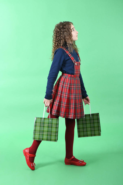 Child with a green packaging checkered texture isolated on green background. Girl likes shopping on sale season. Holiday present, shopping.  - Foto, Bild