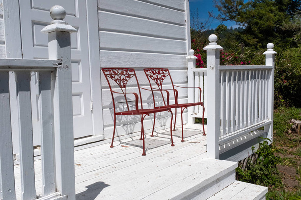Két piros díszes fém szék egy fehér fából készült terasz - Fotó, kép