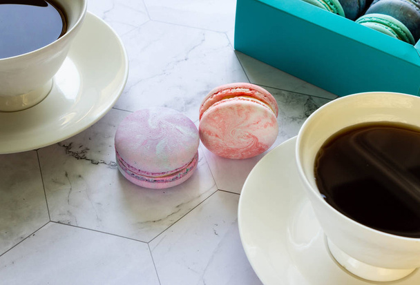 macarons multicolores sur une table en marbre. tasses blanches de thé ou de café. petit déjeuner avec dessert
 - Photo, image
