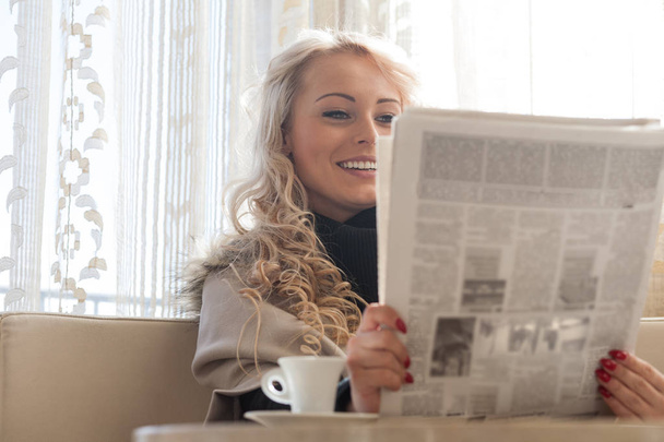 Ładna młoda blond kobieta czytając poranny papier - Zdjęcie, obraz