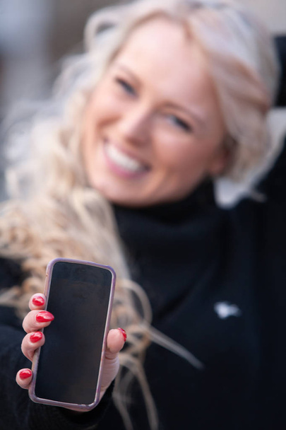glücklich lachende Frau hält ihr Handy hin - Foto, Bild