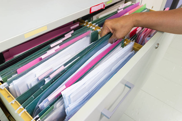 Χέρι του Man αναζήτηση αρχείων έγγραφο σε ένα ντουλάπι αρχείων στο γραφείο εργασίας - Φωτογραφία, εικόνα