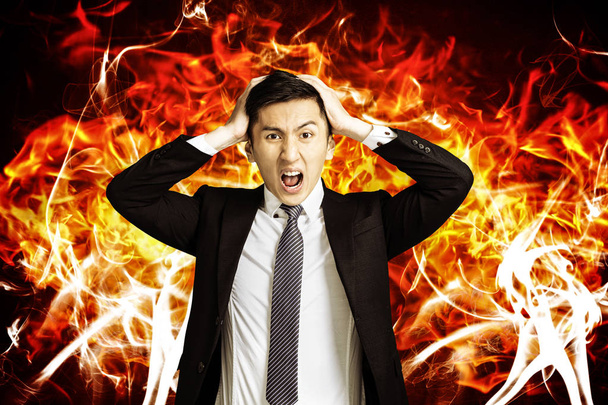 vihainen nuori liikemies, jolla on palava tulinen tausta
 - Valokuva, kuva