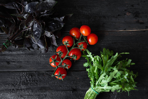 a twig of delicious fresh cherry tomatoes, basil arugula lie on  - Photo, Image