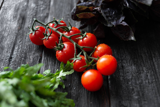 juicy appetizing cherry tomatoes with basil arugula lie on a vin - Photo, Image