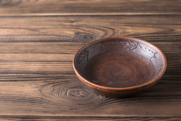 Clay bowl on a brown wooden table. - Photo, image