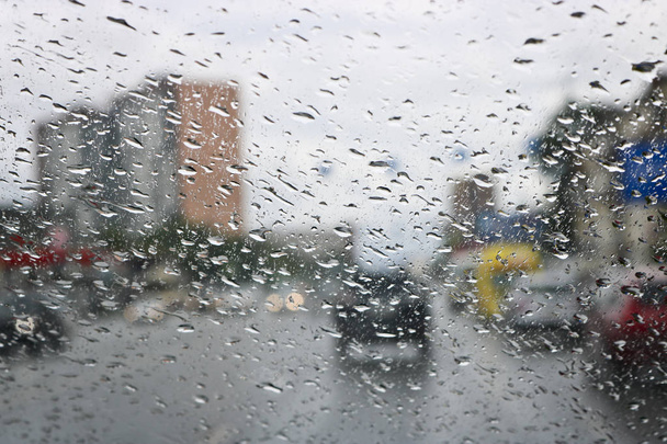 Σταγόνες βροχής στο παρμπρίζ του αυτοκινήτου. Επιλεκτική εστίαση. Η θέα από το παράθυρο του αυτοκινήτου στο οδικό δρόμο. Κακή ορατότητα. - Φωτογραφία, εικόνα