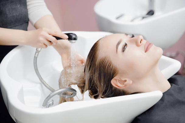 Beautiful blond woman getting hair wash in beauty salon - Foto, Imagem