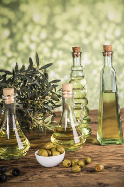 Оливковое масло, оливковое дерево и зеленые и черные оливки на деревянной вкладке
 - Фото, изображение