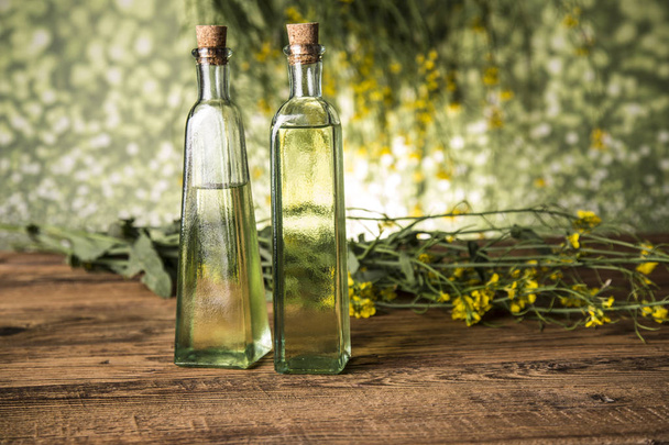 Rapeseed flowers and rapeseed oil in a bottle on the table - Fotó, kép