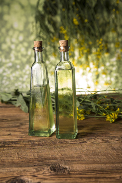 Rapeseed flowers and rapeseed oil in a bottle on the table - Foto, Imagem