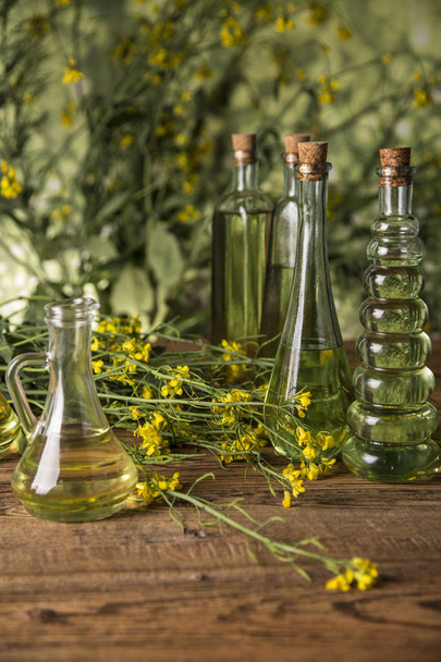 Rapeseed flowers and rapeseed oil in a bottle on the table - Foto, immagini