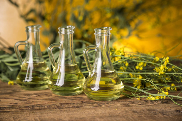 Kwiaty rzepaku i olej rzepakowy w butelce na stole - Zdjęcie, obraz