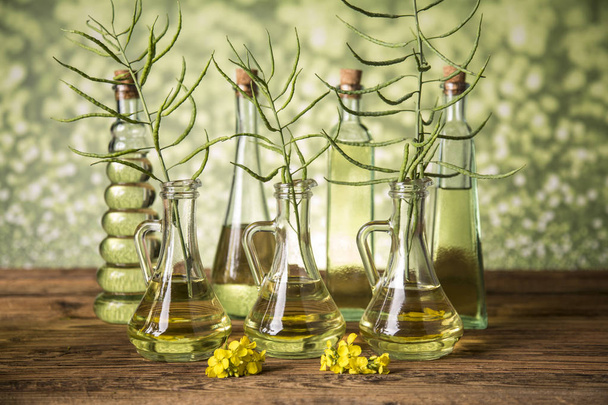 Seeds and rape flowers in bottles and carafes with rapeseed oil - Фото, зображення